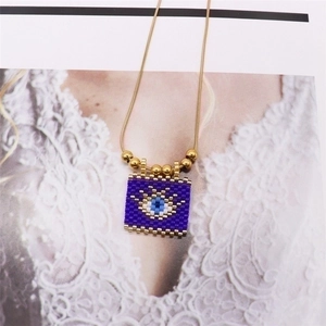 Macro detail of Bohemian evil eye beaded pendant necklace with golden metal accents