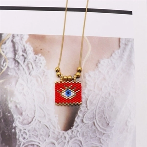 Detail of red handmade beaded evil eye pendant with tiny gold beads and a fine snake chain