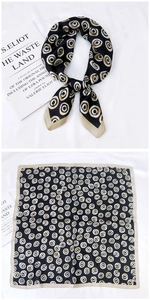 Détail d'un foulard carré en soie avec cercles géométriques noué et posé à plat sur tissu