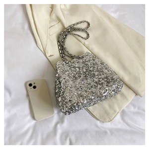 Close-up of a silver sequined bucket bag with a chain strap on a beige blazer