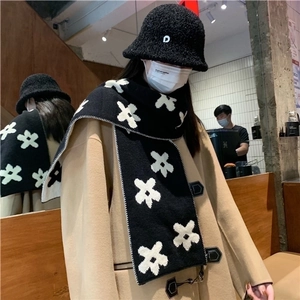Women's black knit scarf with white floral pattern and matching fisherman hat in a cafe setting