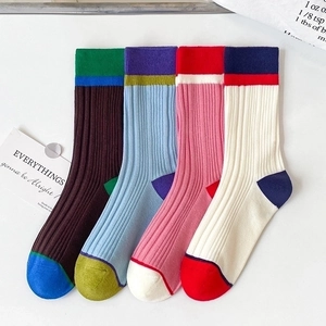 Detailed knit texture of four pairs of colorful contrast mid-calf cotton socks on a white desk