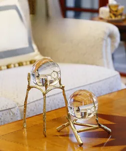 Close-up of dual crystal ball ornaments with textured brass branch bases on wood table