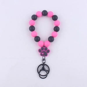 Detail of pink and black silicone bead bracelet with a paw print charm and metal keyring