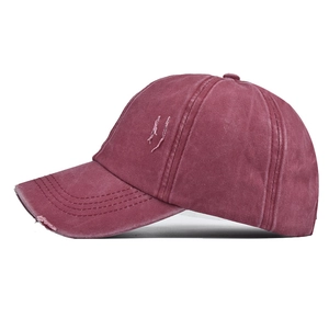 Detail of distressed ponytail baseball cap in burgundy with side ripped holes and frayed brim