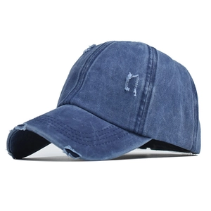 Detailed view of dark blue washed denim baseball cap with vintage distressed ripped holes