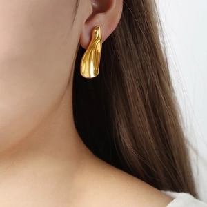 Irregular liquid metal gold stud earrings with minimalist trendy aesthetic on model