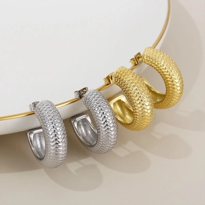 Macro shot of 18K gold and silver C-shaped earrings with fine fish scale texture