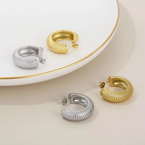 Detail view of gold and silver C-shaped earrings with textured snake scale patterns
