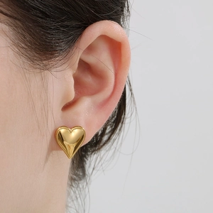 Close-up of minimalist heart-shaped 18K gold earrings worn by a model