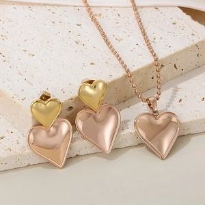 Two-tone gold and silver heart jewelry set featuring earrings and a beaded necklace on stone