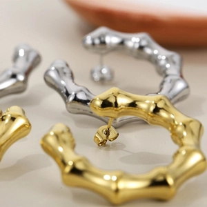 Detail of gold and silver C-shaped bamboo texture earrings in polished stainless steel