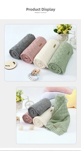 Detailed view of soft knitted baby blankets with waffle texture and leather logo tags