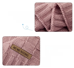 Detail of dusty pink knit baby blanket featuring chunky texture and premium leather tag