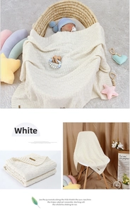 Detail of off-white knitted baby blanket with soft waffle texture and leather logo tag