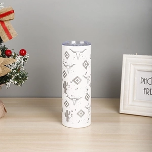 Detail of 20oz white tumbler with cow skull and cactus patterns on a wooden surface