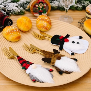Three gnome Christmas cutlery holders with festive hats on a woven table tray