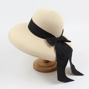 Detailed view of beige woven straw hat texture with a large decorative black bow ribbon