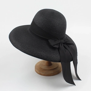 Close-up of a black wide-brim straw hat featuring a large elegant matching ribbon bow