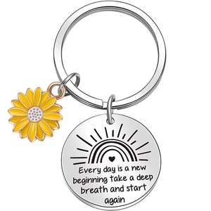 Macro view of stainless steel keychain with engraved quote and sunflower charm