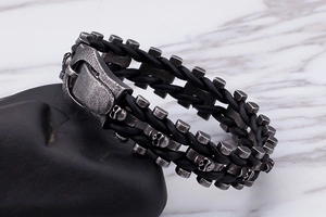 Detail of punk braided leather bracelet with vintage silver skull charms on a stone