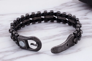Detail of black braided leather and silver steel links with hook clasp on marble surface