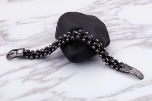 Detail of black braided leather bracelet with silver skull charm and magnetic clasp