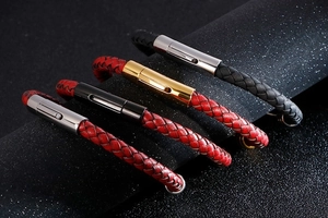Close-up of four woven leather bracelets in red, gold, black and silver with metal clasps