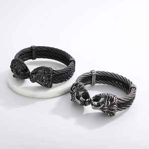 Detailed view of dual lion head charms on a black braided steel cable men's bracelet