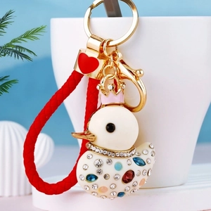 Close-up of white crystal duck keychain with pink crown, red braid, and gold metal clasp