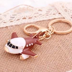 Brown and white airplane keychain with crystal rhinestones on beige burlap background