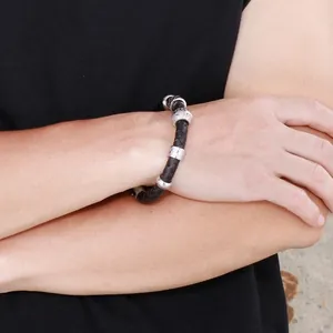 Détail du bracelet en cuir tressé noir de 10mm avec perles en acier argenté sur le poignet