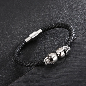 Macro view of black braided leather bracelet with silver skull details and magnetic clasp