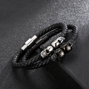 Detail of woven leather bracelets with silver and black skull beads and magnetic clasps