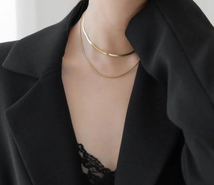 Dubbellaagse goudkleurige slangenketting op model met zwarte blazer en kant