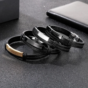 Close-up of men's braided leather bracelets with engraved stainless steel metal plates
