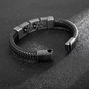 Detail of black braided leather men's bracelet with dark metal clasp and punk style texture
