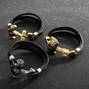 Macro view of multi-layer braided leather bracelets with anchor and compass metal charms