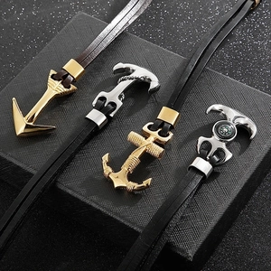 Detail view of anchor pendants with compass motifs on multi-layer leather bracelets