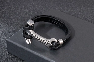Detail of multi-layer black braided leather bracelet with silver hammer charm