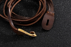 Macro shot of brown braided leather bracelet with a polished gold fish hook clasp