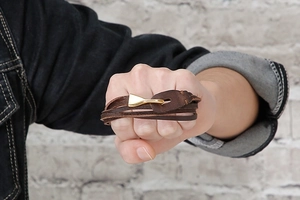 Close-up of a men's dark brown multi-layer braided leather bracelet with golden hook clasp