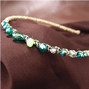 Handmade headband with green and clear crystal beads on a gold metal frame