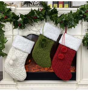 Trois chaussettes de Noël tricotées avec revers en fourrure sur une cheminée