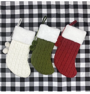 Détail de trois chaussettes de Noël tricotées rouges, vertes et blanches sur tissu à carreaux