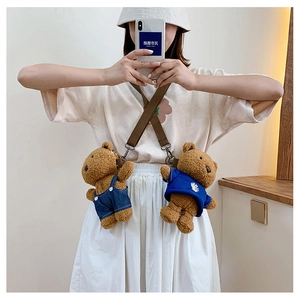 Detail of plush bear crossbody bags with denim overalls and floral shirt on a model