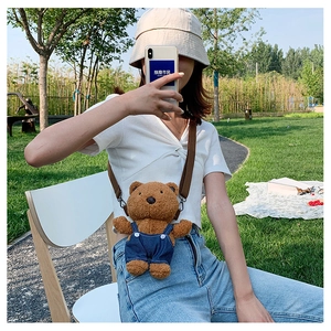 Detail of cute teddy bear plush crossbody bag with denim overalls and adjustable strap