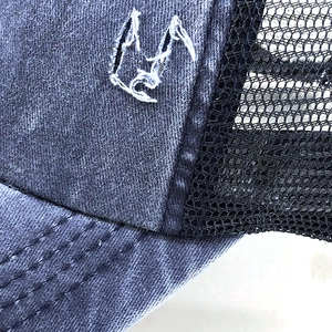 Detail of washed denim trucker hat featuring breathable mesh and reinforced brim stitching