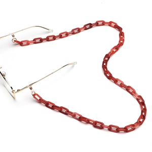 Dettaglio catena per occhiali in acrilico ambra rossa con maglie in resina e metallo oro