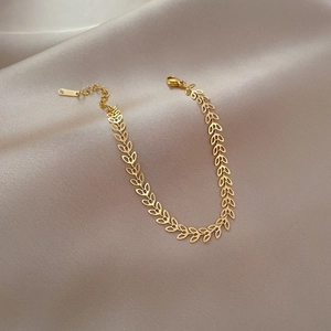 Minimalist gold titanium steel clover leaf chain bracelet on a soft satin cloth
